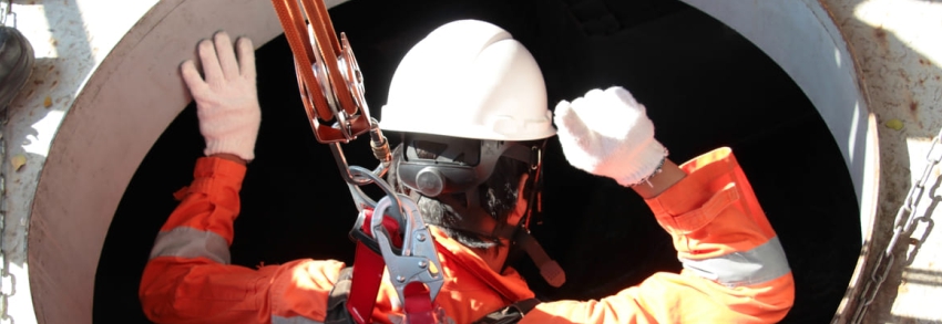 muncitor cu echipament de protectie coborat in bazin colector